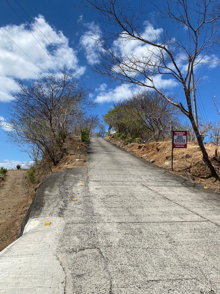 A very steep laneway going upwards. A sign is posted at the base saying entry prohibited.