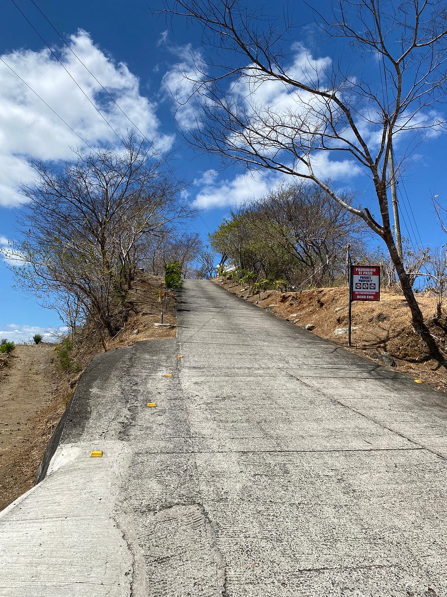 A very steep laneway going upwards. A sign is posted at the base saying entry prohibited.