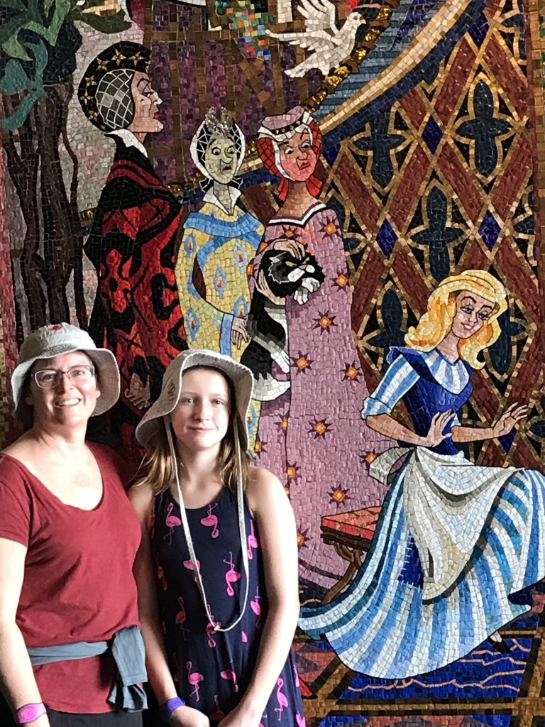 Woman and her daughter in front of princess mosaic at Disney World.
