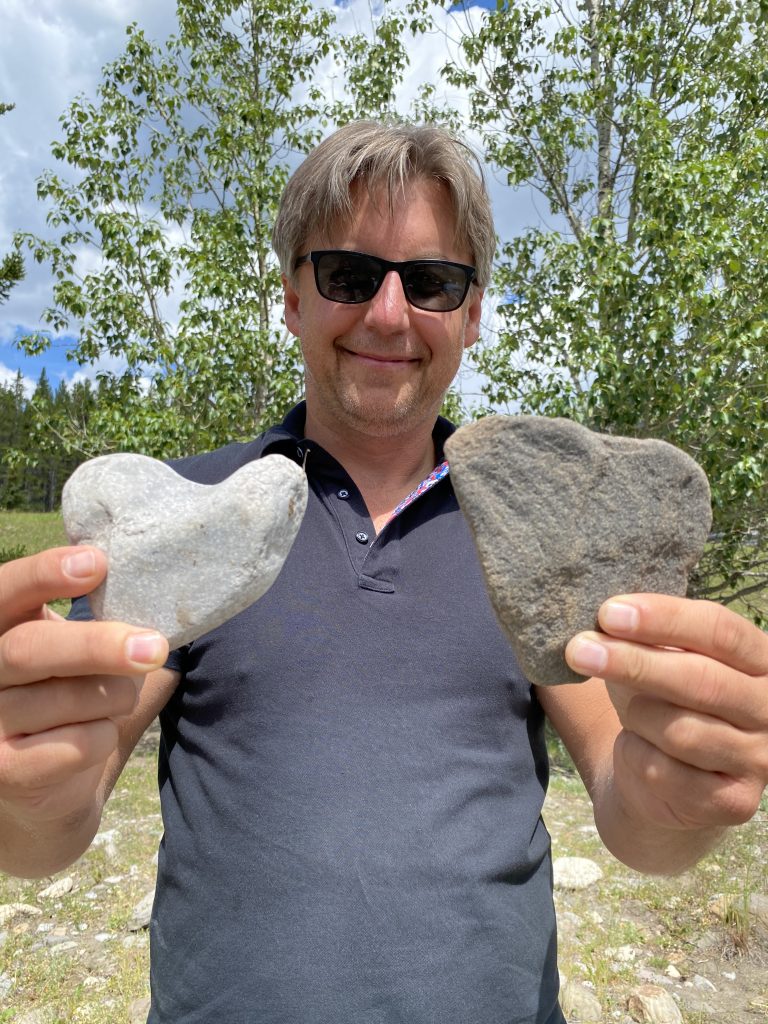 Man holding up two heart-shaped rocks