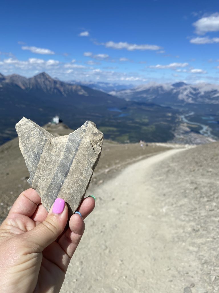 A person holding heart-shaped stone on top of Whistler's Summit in Jasper, Alberta.