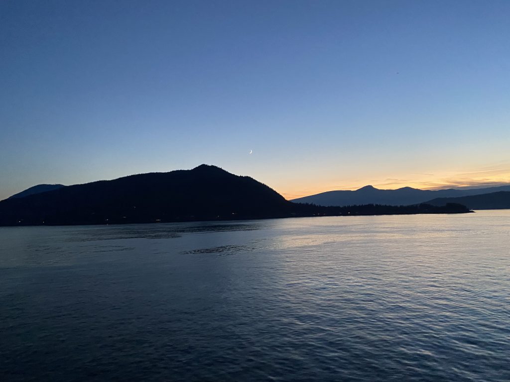 Sunset over mountains by ocean.