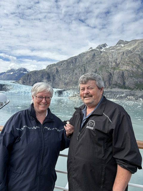 couple with Jesus statue in front of glacier